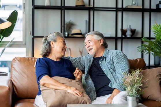 senior couple laughing on a couch for a story on how Matrix telehealth visits help with chronic care management